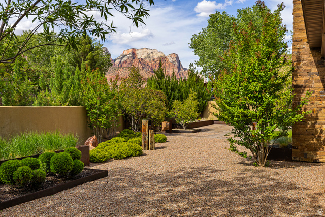 105 River Bend Circle, Unit 105 Springdale, UT 84767 - Photo 38 of 56 Desert landscape featuring a gravel pathway, diverse plantings, and a stone-clad exterior wall