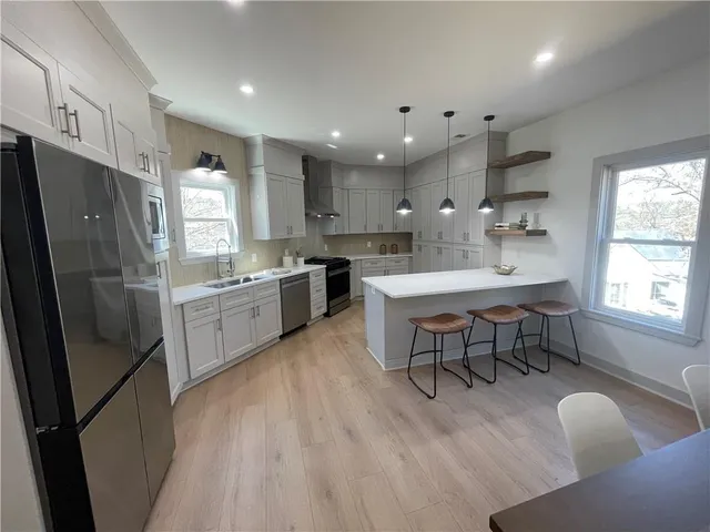 a kitchen with stainless steel appliances granite countertop a refrigerator a sink a stove a dining table and chairs