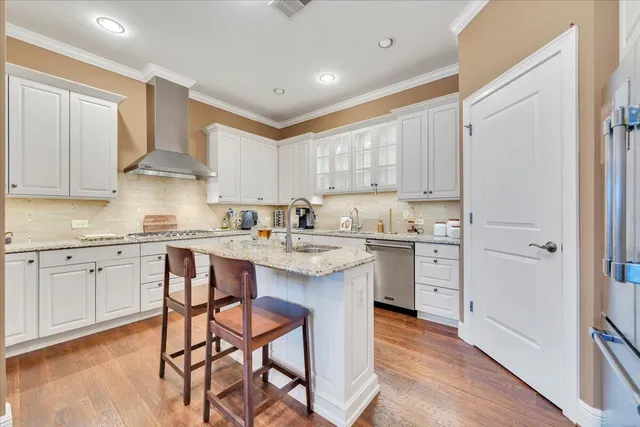 a kitchen with stainless steel appliances granite countertop a table chairs sink and cabinets
