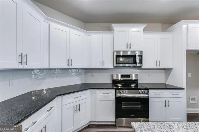a kitchen with granite countertop white cabinets and stainless steel appliances