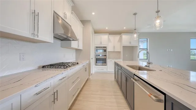 a large kitchen with stainless steel appliances granite countertop a lot of counter space a sink and a wooden floors