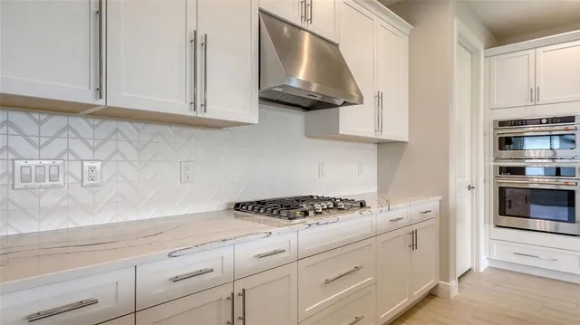 a kitchen with white cabinets and stove