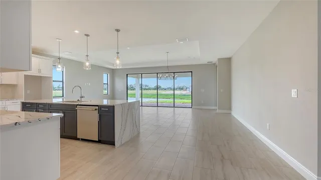 a large kitchen with stainless steel appliances granite countertop a stove a sink a refrigerator and white cabinets with wooden floor