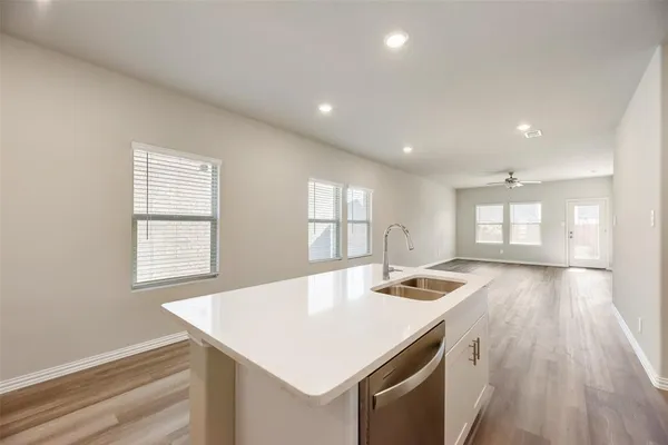 a kitchen with a sink dishwasher a stove and white countertops with wooden floor