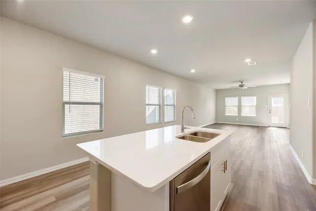 a kitchen with a sink dishwasher a stove and white countertops with wooden floor