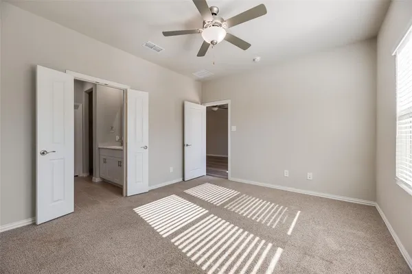 an empty room with closet and a ceiling fan
