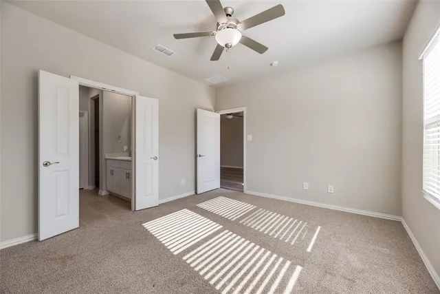 an empty room with closet and a ceiling fan