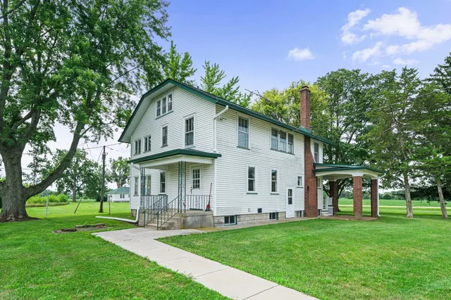 a view of a white house with a big yard and large trees