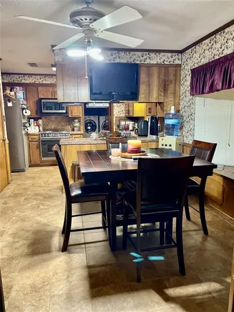 a room with stainless steel appliances kitchen island granite countertop a dining table chairs and a oven
