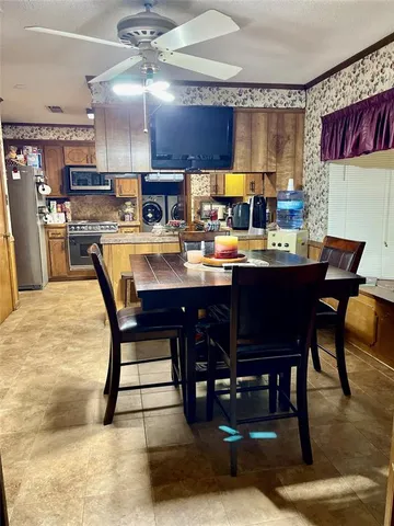 a room with stainless steel appliances kitchen island granite countertop a dining table chairs and a oven