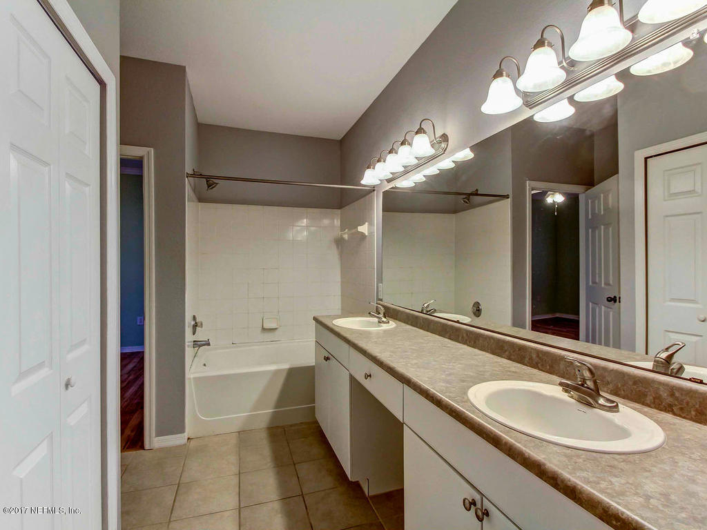 10961 Burnt Mill Road, Unit 1414 Jacksonville, FL 32256 - Photo 23 of 39 a bathroom with a granite countertop sink a large mirror and a bathtub
