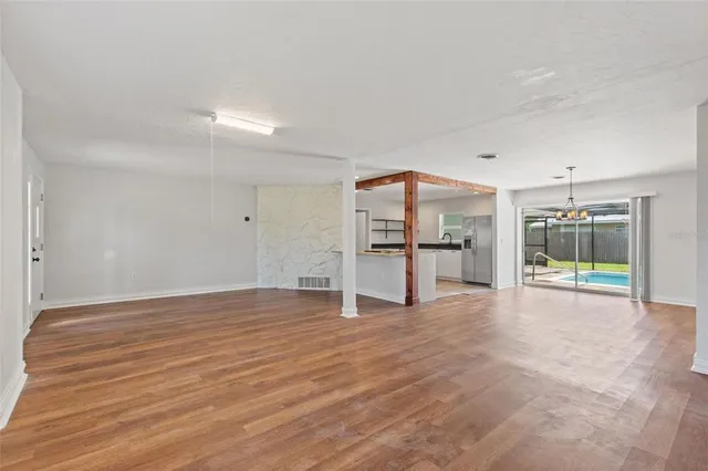 a view of a room with wooden floor kitchen appliances and a ceiling fan
