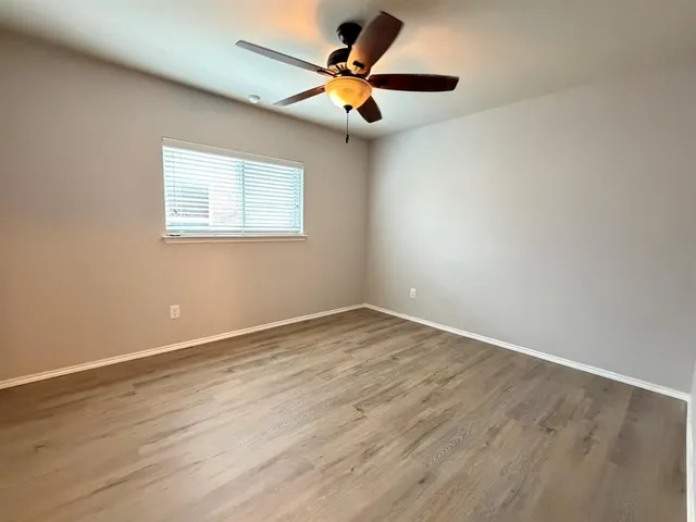 a view of an empty room with window and wooden floor