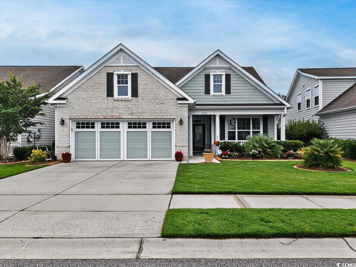 View of front of property featuring driveway, brick siding, and a front lawn