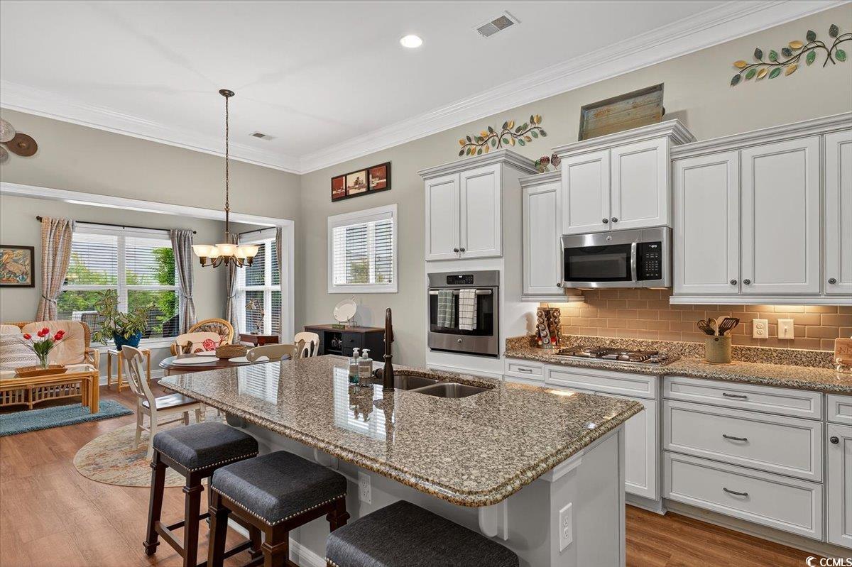 1719 Maplecress Way Myrtle Beach, SC 29577 - Photo 13 of 40 Kitchen with appliances with stainless steel finishes, ornamental molding, a chandelier, a breakfast bar area, and wood finished floors