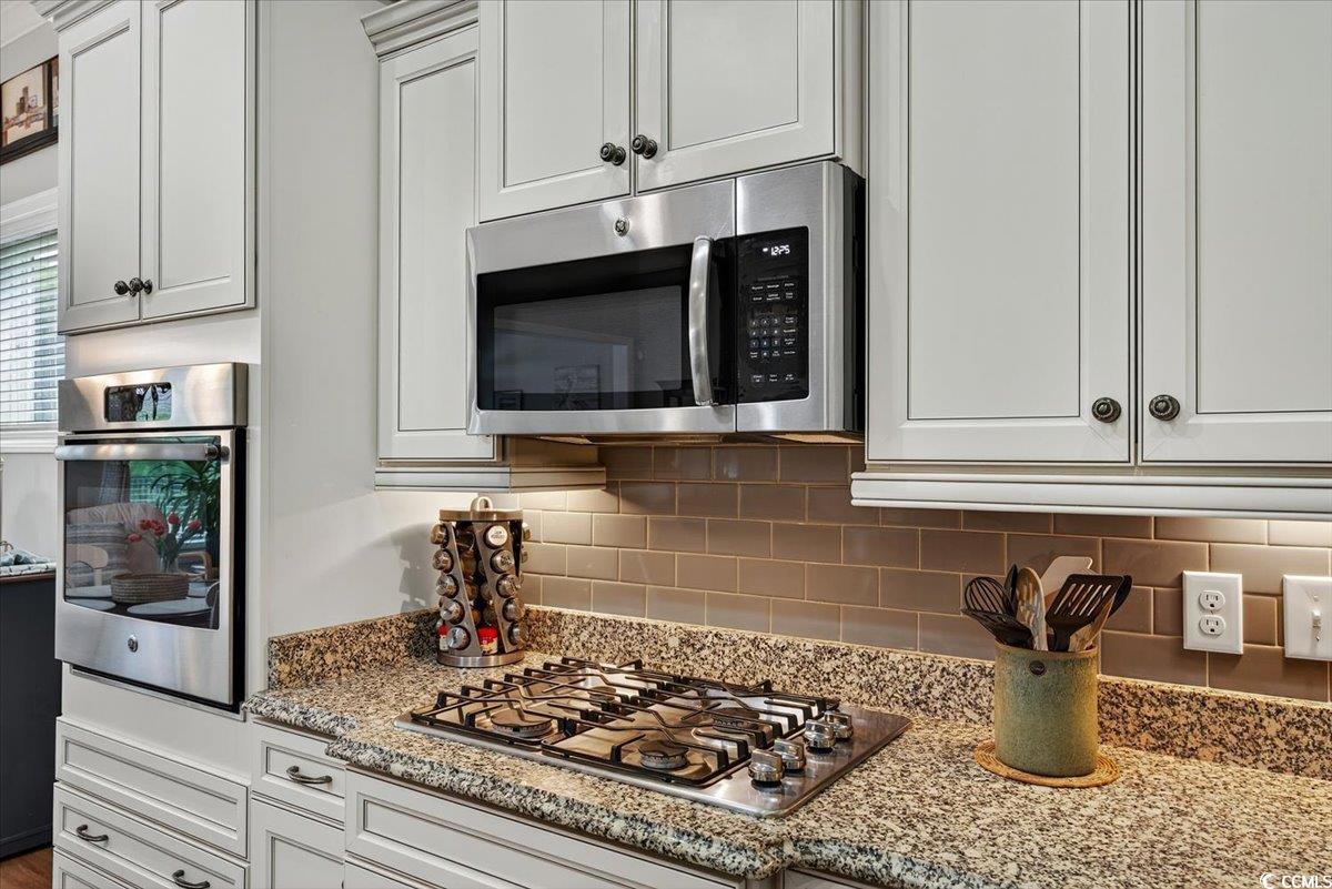 1719 Maplecress Way Myrtle Beach, SC 29577 - Photo 14 of 40 Kitchen featuring appliances with stainless steel finishes, tasteful backsplash, light stone counters, and white cabinetry