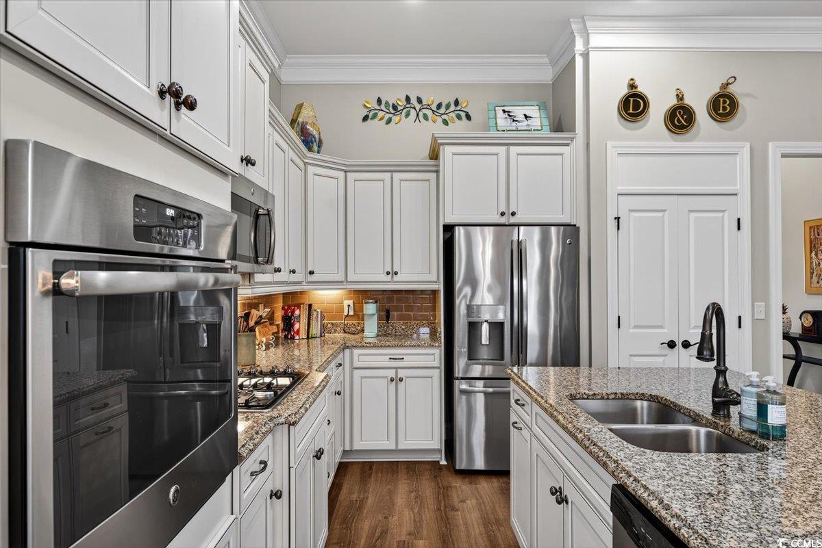 1719 Maplecress Way Myrtle Beach, SC 29577 - Photo 15 of 40 Kitchen with appliances with stainless steel finishes, crown molding, white cabinets, decorative backsplash, and light stone counters