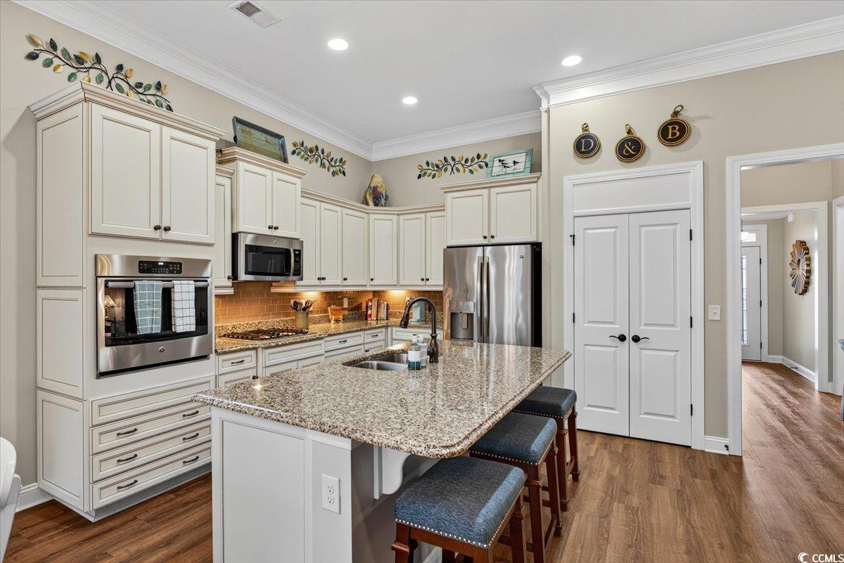 1719 Maplecress Way Myrtle Beach, SC 29577 - Photo 16 of 40 Kitchen with stainless steel appliances, dark wood finished floors, light stone counters, a breakfast bar, and backsplash