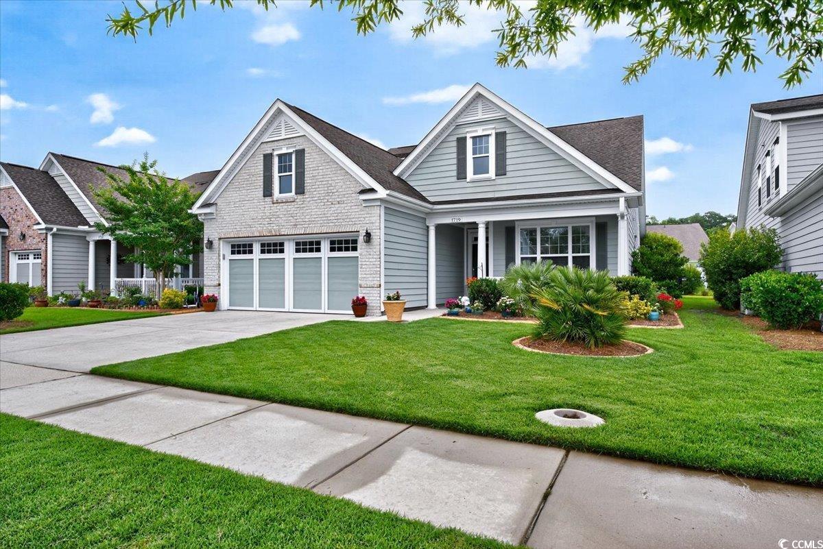 View of front of house featuring driveway, a front lawn, a garage, and a porch