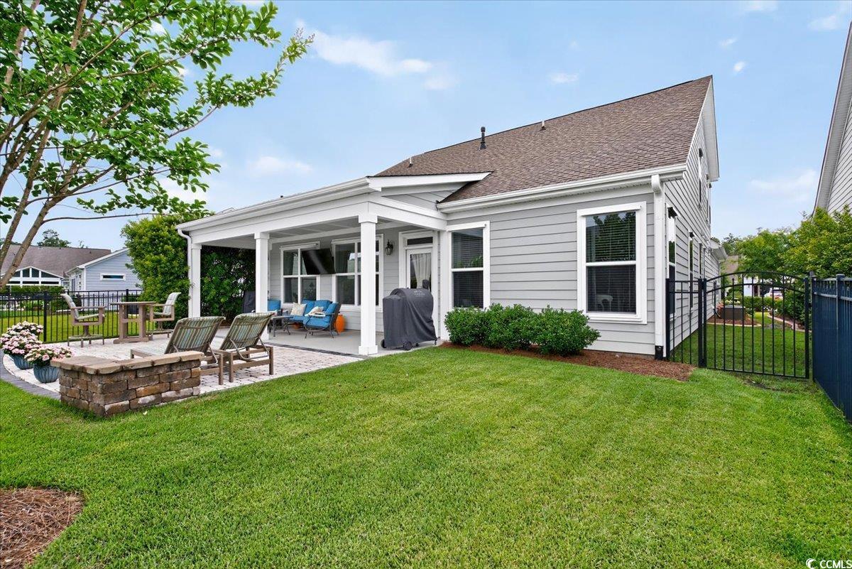 Back of house featuring a patio, roof with shingles, and a gate