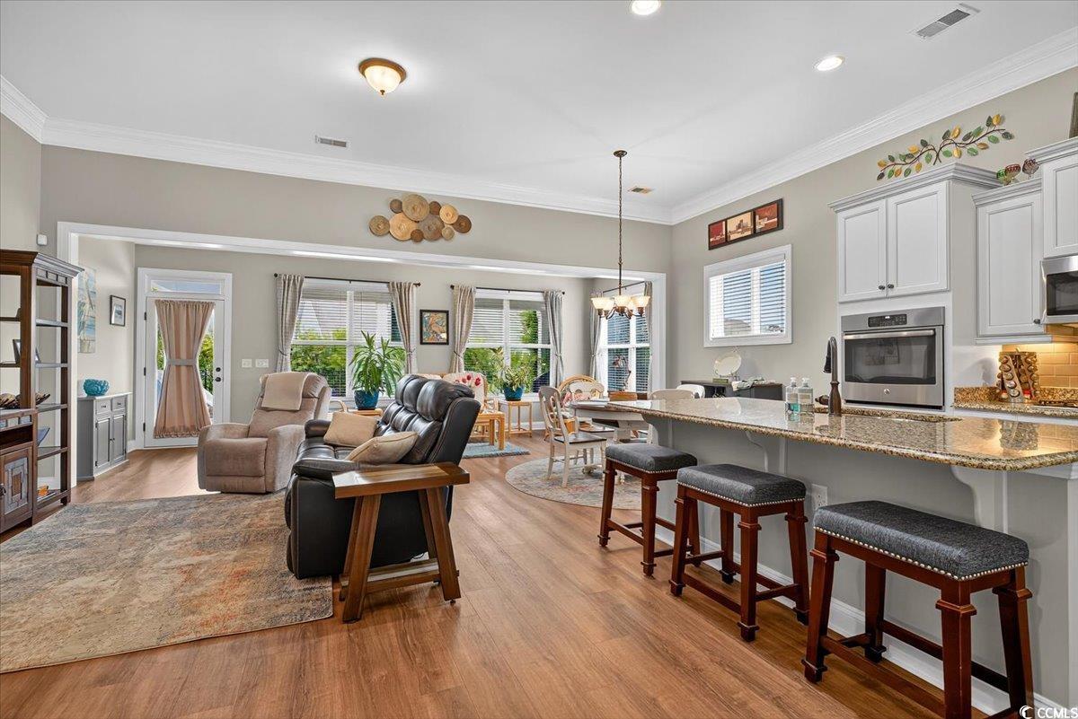 Living room featuring a chandelier, light wood finished floors, crown molding, and recessed lighting