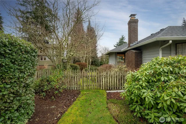 a view of a house with a small yard plants and large tree