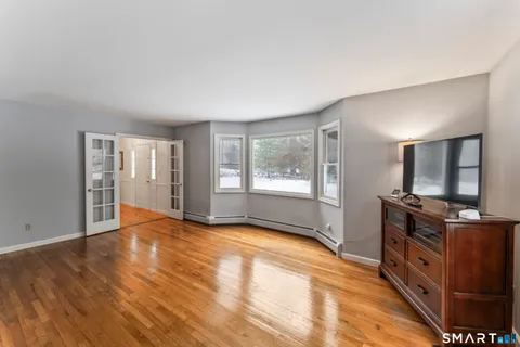 a view of an empty room with window and wooden floor