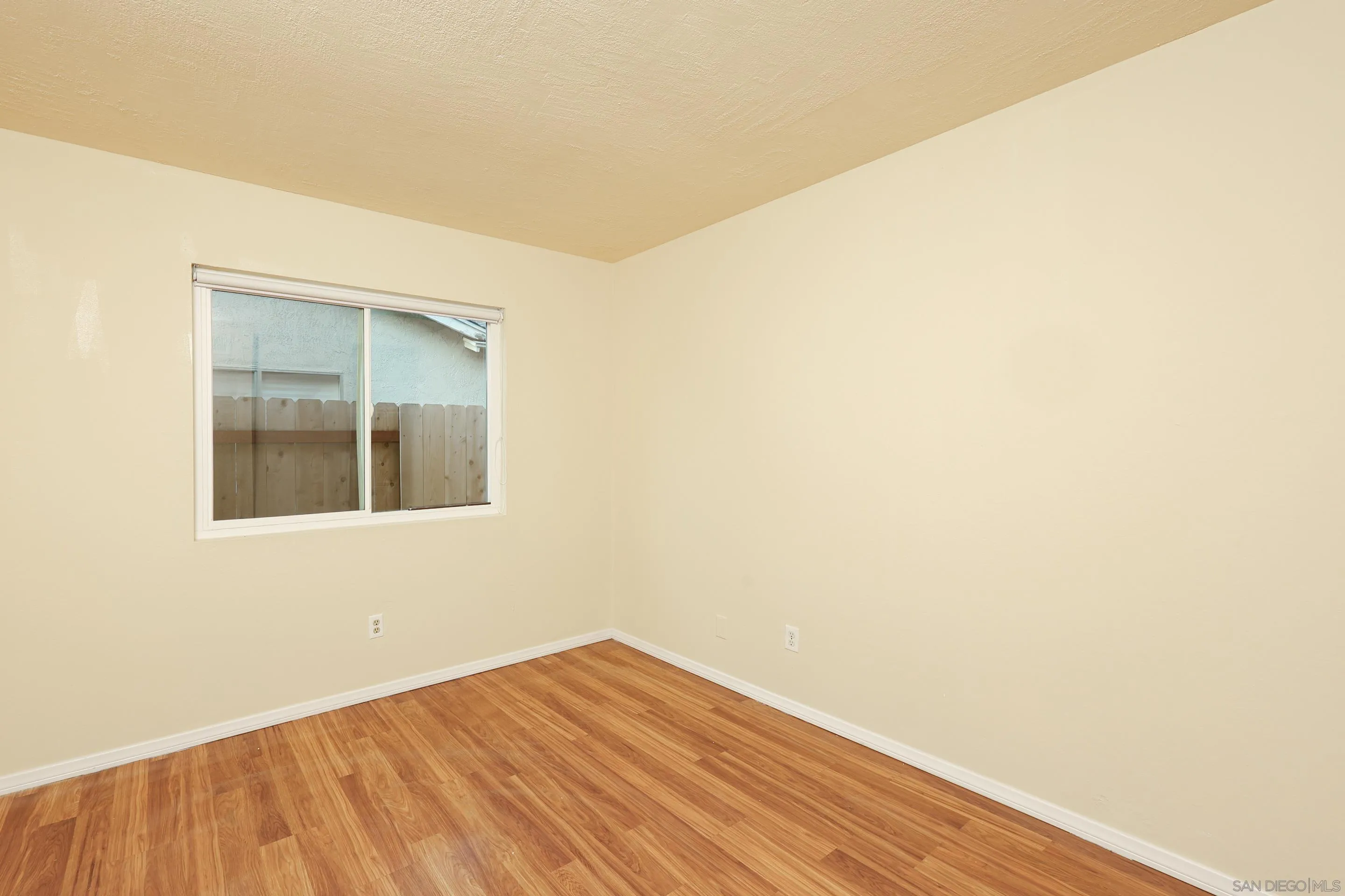 10866 Sandy Hook Road San Diego, CA 92126 - Photo 9 of 15 a view of an empty room with wooden floor and a window