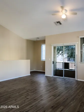 a view of empty room with wooden floor and fan