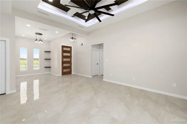 an empty room with chandelier fan and windows