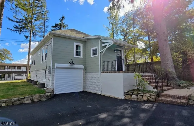 a view of a white house with a large tree and wooden fence