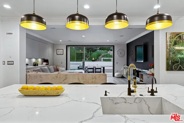 a kitchen with stainless steel appliances kitchen island granite countertop a dining table chairs and view of living room