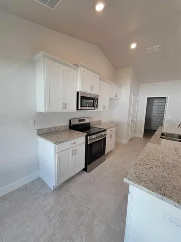 a kitchen with granite countertop white cabinets and stainless steel appliances