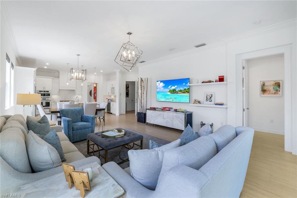 a living room with furniture kitchen view and a chandelier