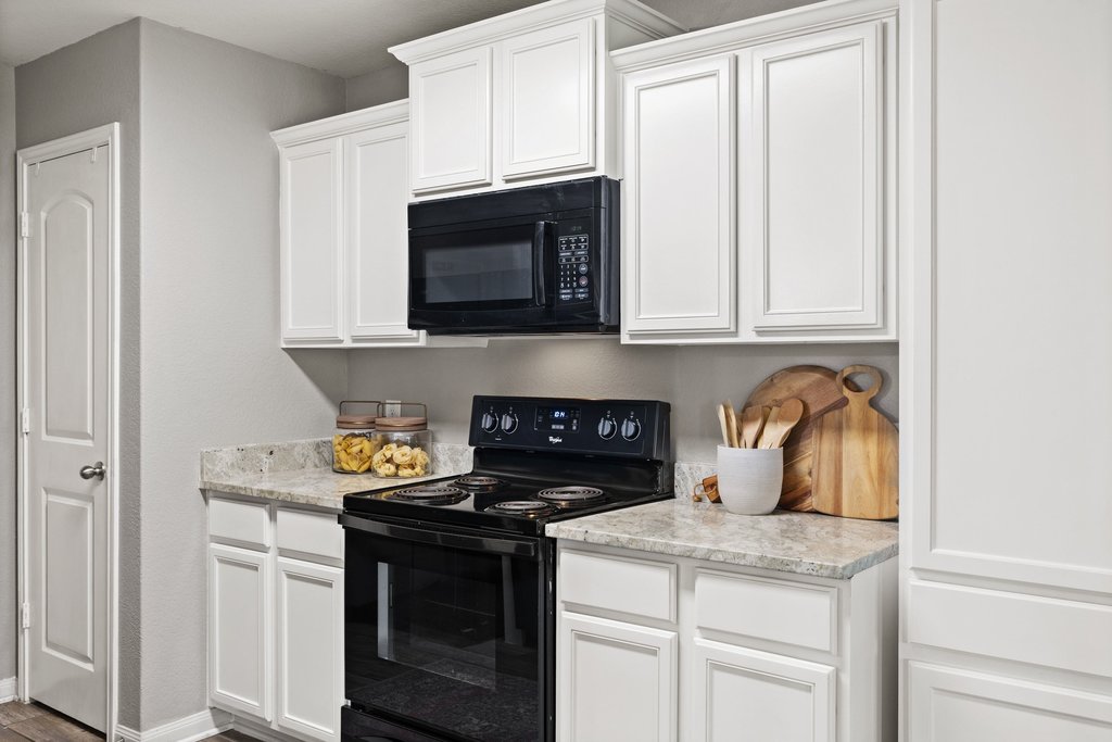 217 Farmer Lane Jarrell, TX 76537 - Photo 6 of 29 Modern kitchen with white cabinetry and a built-in microwave over the range.