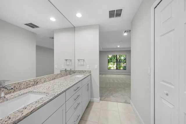 a bathroom with a granite countertop sink a toilet and with mirror