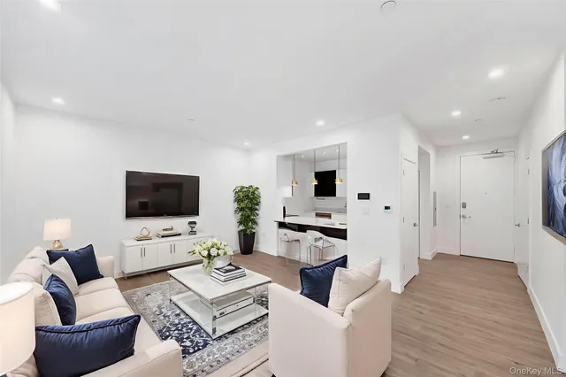a living room with furniture a flat screen tv and a refrigerator