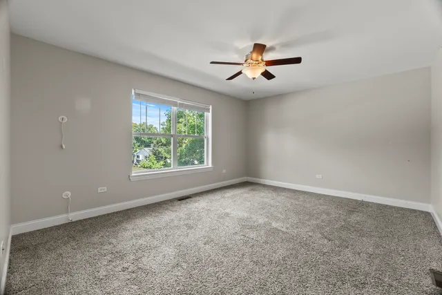 an empty room with windows and fan