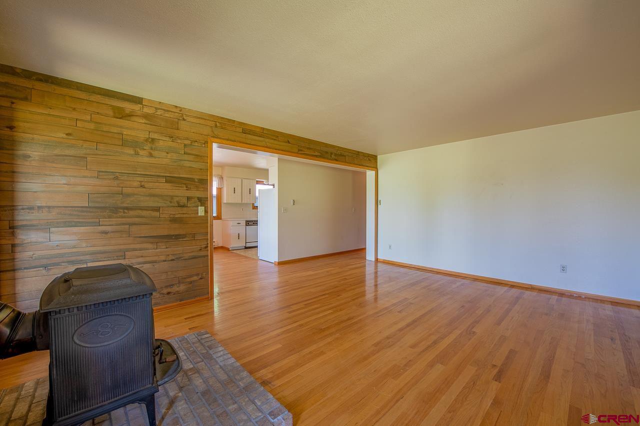 171 Arapahoe Road Gunnison, CO 81230 - Photo 8 of 34 Hardwood floors, wood burning stove, electric baseboard heat, and plenty of windows.