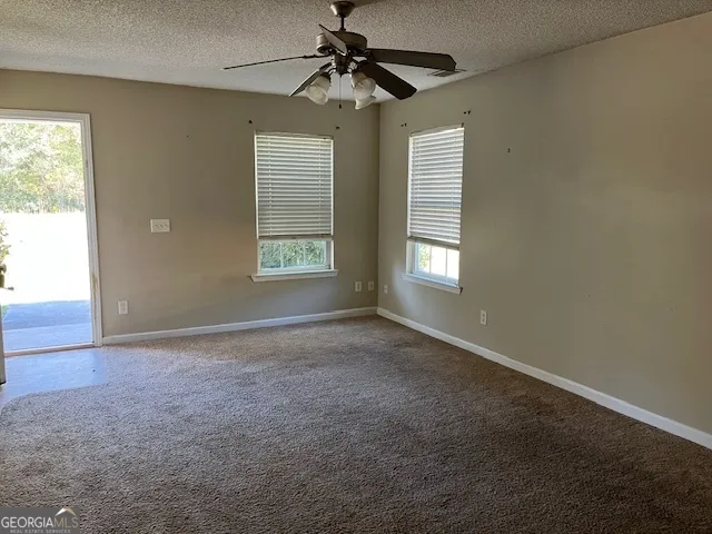 an empty room with windows and fan