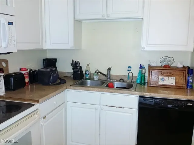 a kitchen with stainless steel appliances granite countertop a sink a stove and white cabinets