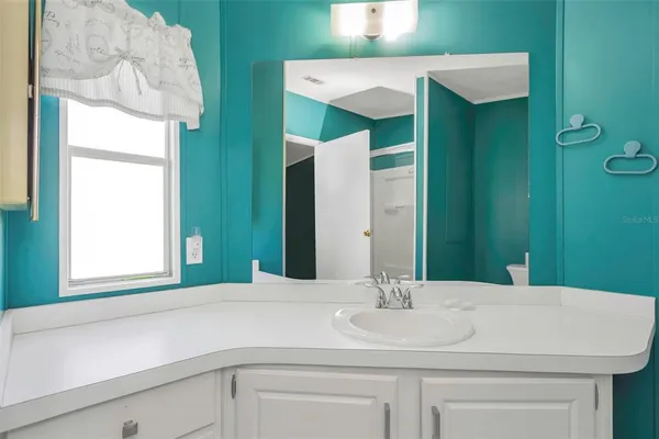 a bathroom with a granite countertop shower sink vanity and mirror