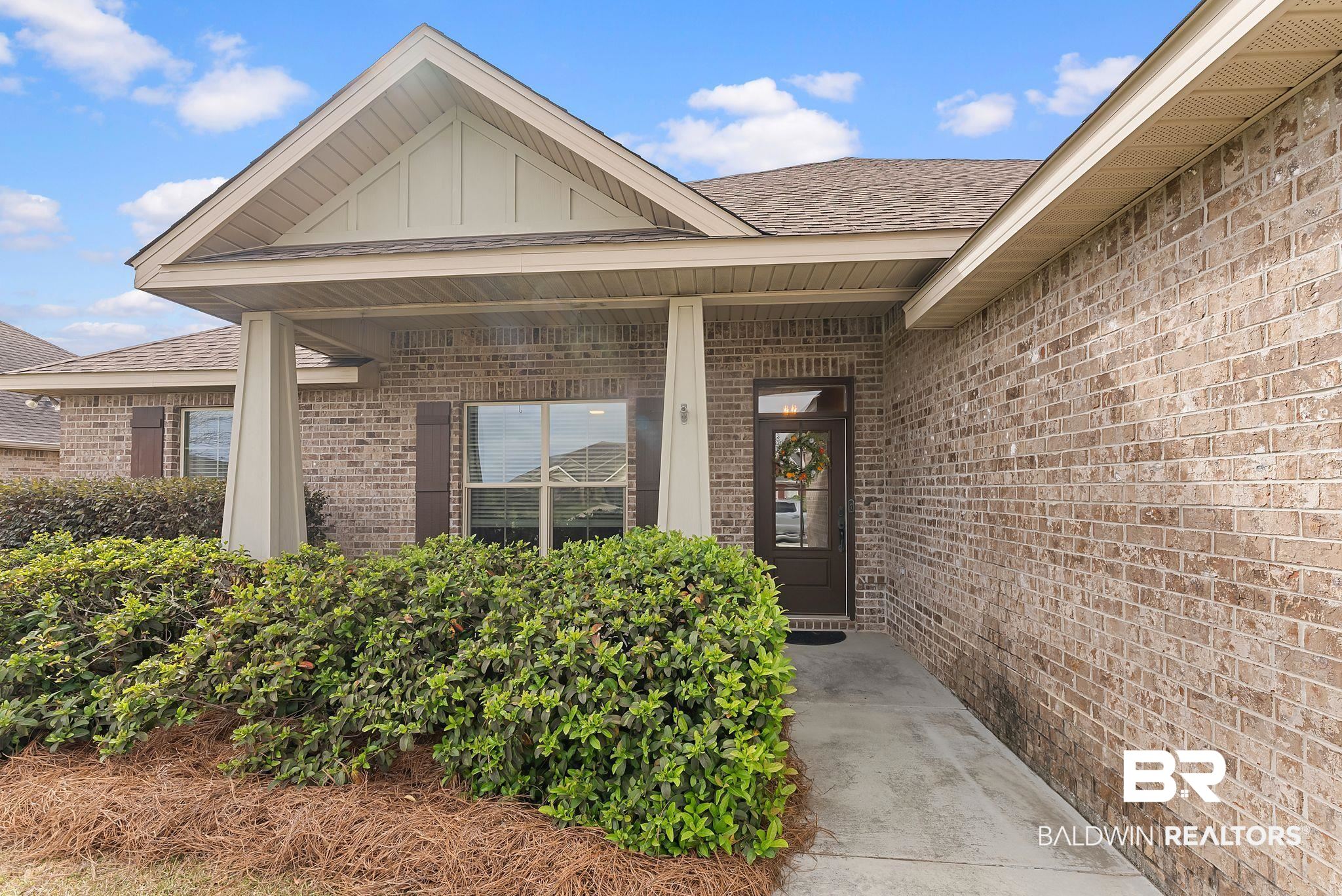 7015 Rocky Rd Loop Gulf Shores, AL 36542 - Photo 4 of 41 Doorway to property with board and batten siding, brick siding, a porch, and roof with shingles