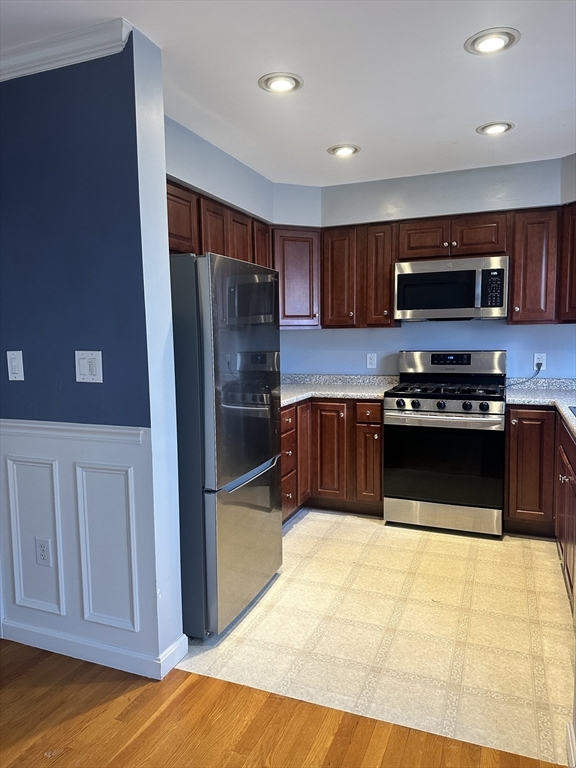 3 Bancroft Avenue, Unit 3 Reading, MA 01867 - Photo 9 of 19 a kitchen with stainless steel appliances a stove a microwave and a refrigerator
