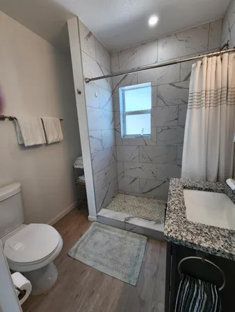 a bathroom with a granite countertop toilet a sink and a shower