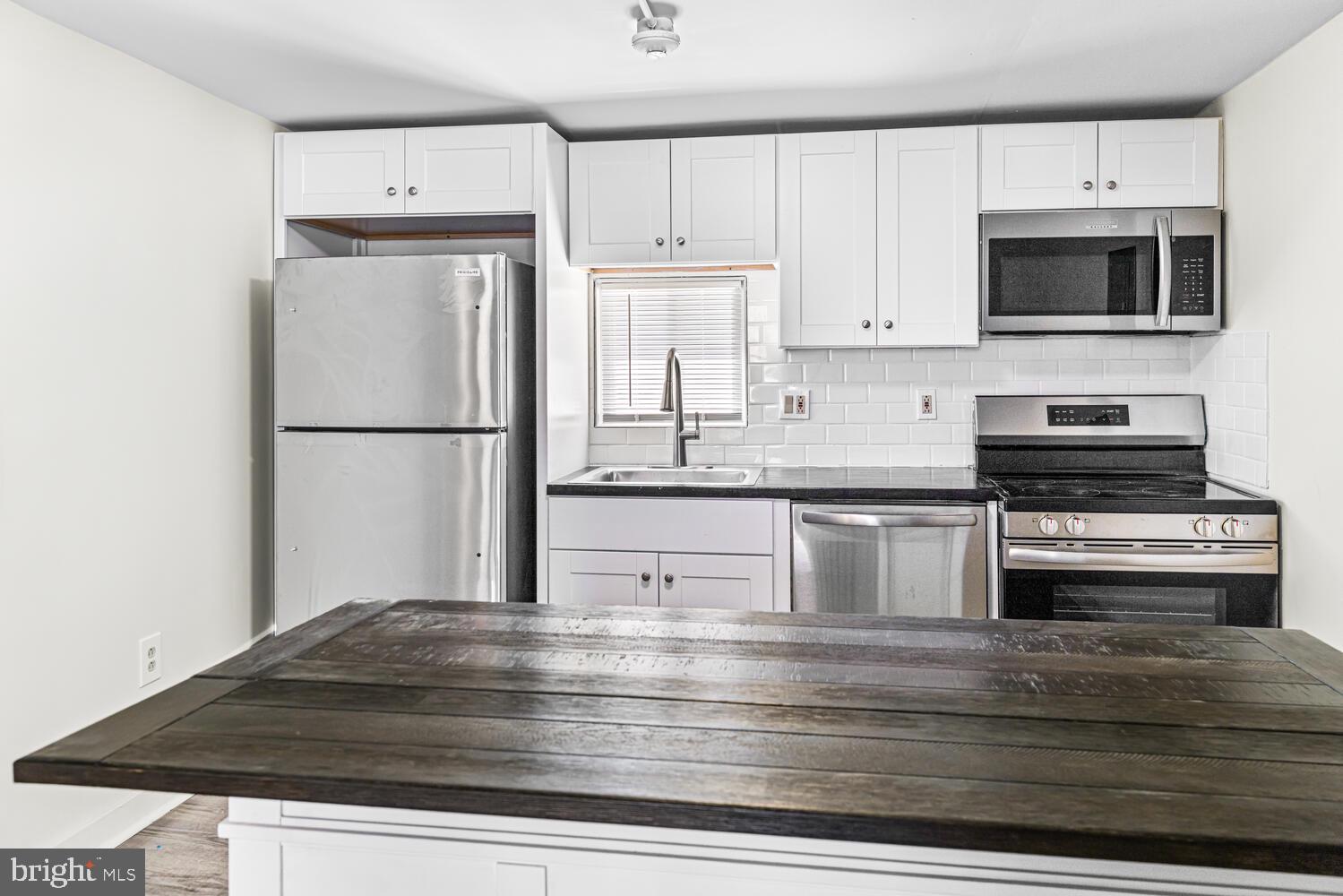 178 Master Street Philadelphia, PA 19122 - Photo 8 of 19 a kitchen with stainless steel appliances granite countertop a refrigerator stove a sink and a microwave