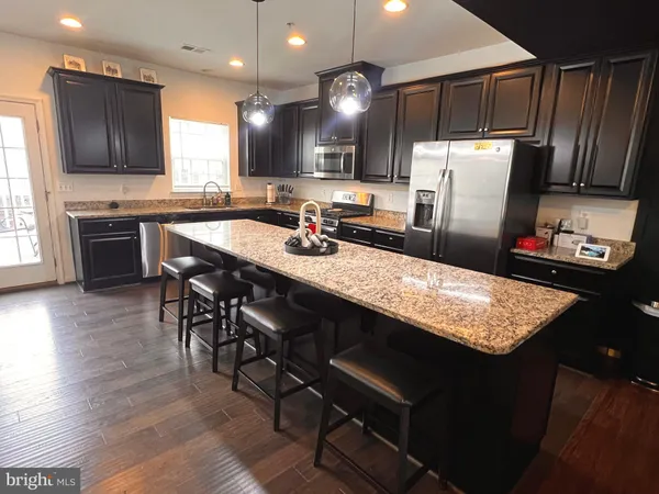 a kitchen with stainless steel appliances granite countertop a table chairs sink refrigerator and microwave