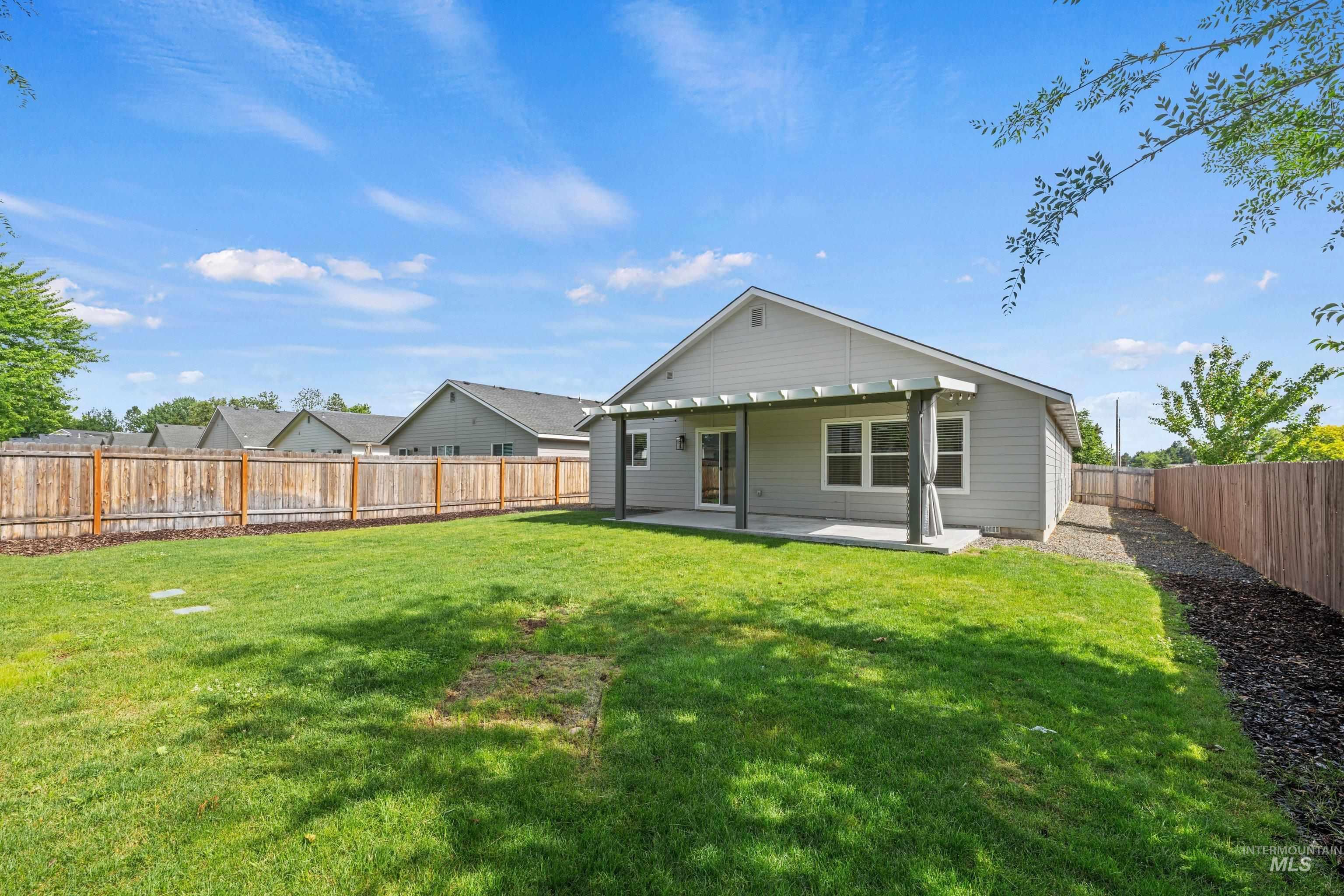 12744 West Fig Street Boise, ID 83713 - Photo 30 of 34 Spacious backyard featuring a manicured lawn, full wood fencing, and a covered patio with a pergola
