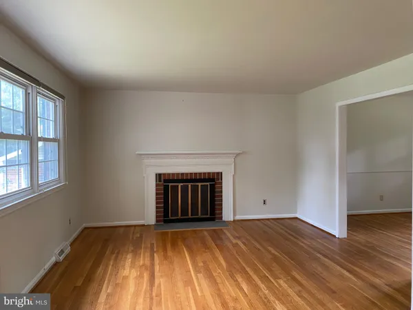 an empty room with wooden floor a fireplace and windows