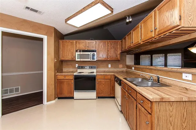 a kitchen with stainless steel appliances granite countertop a sink a stove and a refrigerator